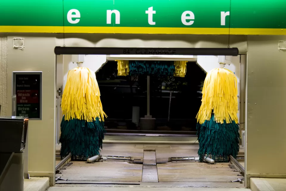 Entrance to a drive-through car wash at night with green 'Enter' sign.